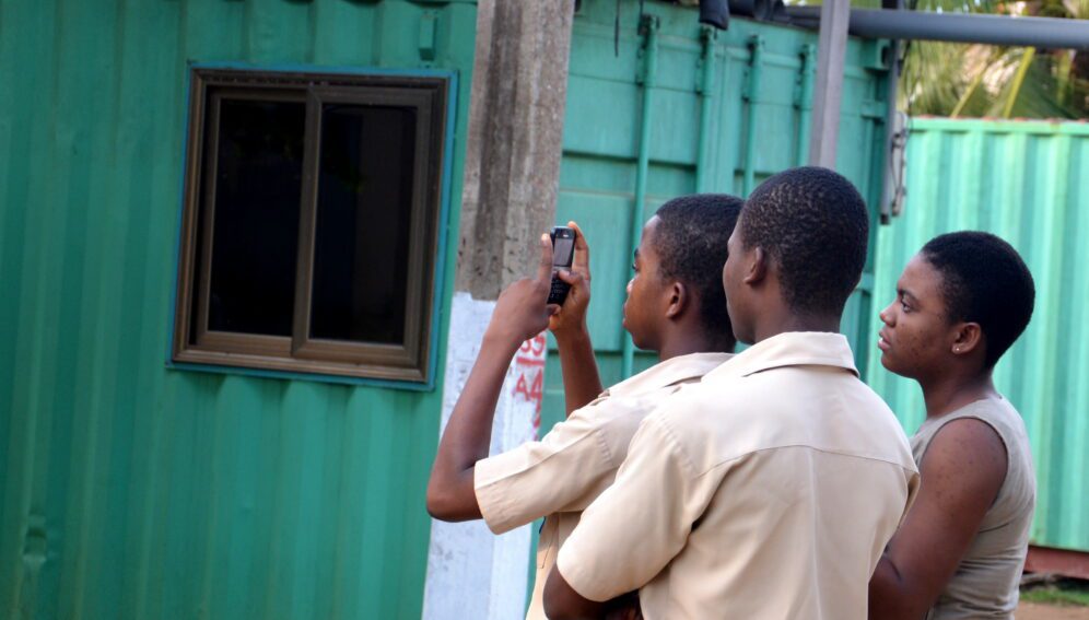 Des eleves africains dont l'un tient en main un telephone. 
Credit image : Flickr / Michael Pollak