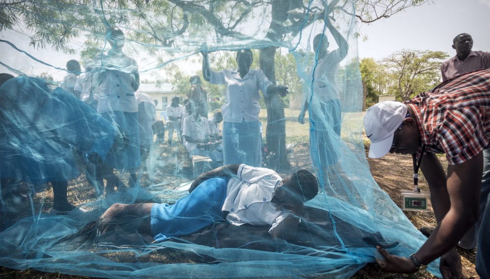 Community health workers demonstrate the use of mosquito nets