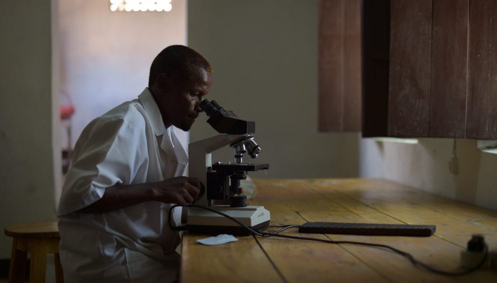 A lab technician checks a blood sample for malaria