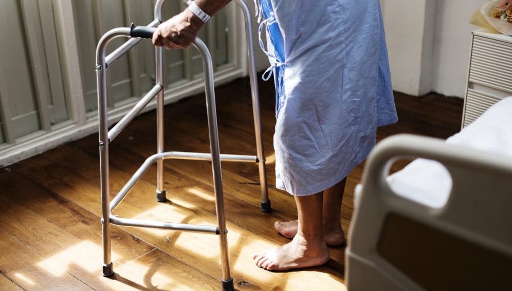 A sick man tries to walk using walking aid