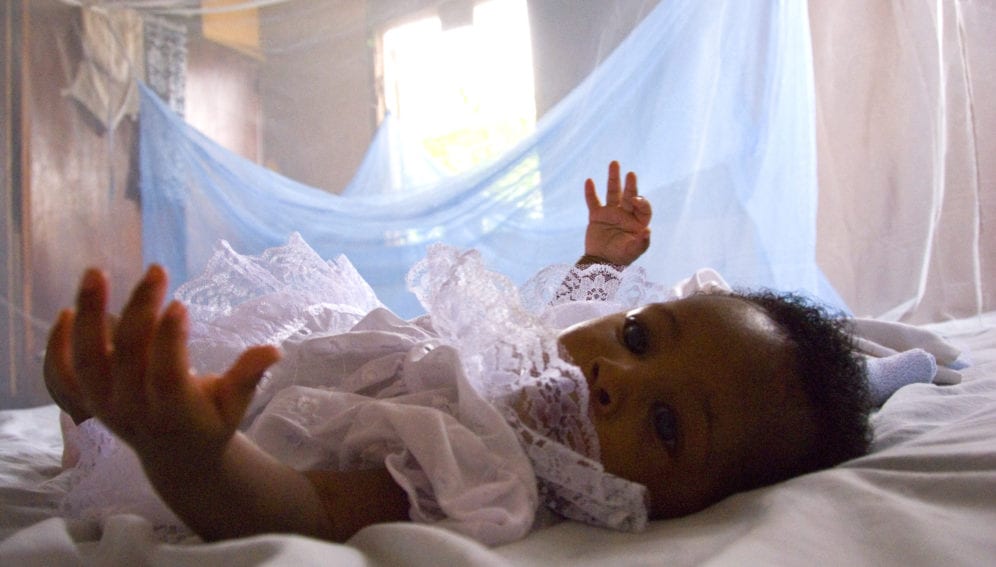 Infant surrounded by protective malaria bed net