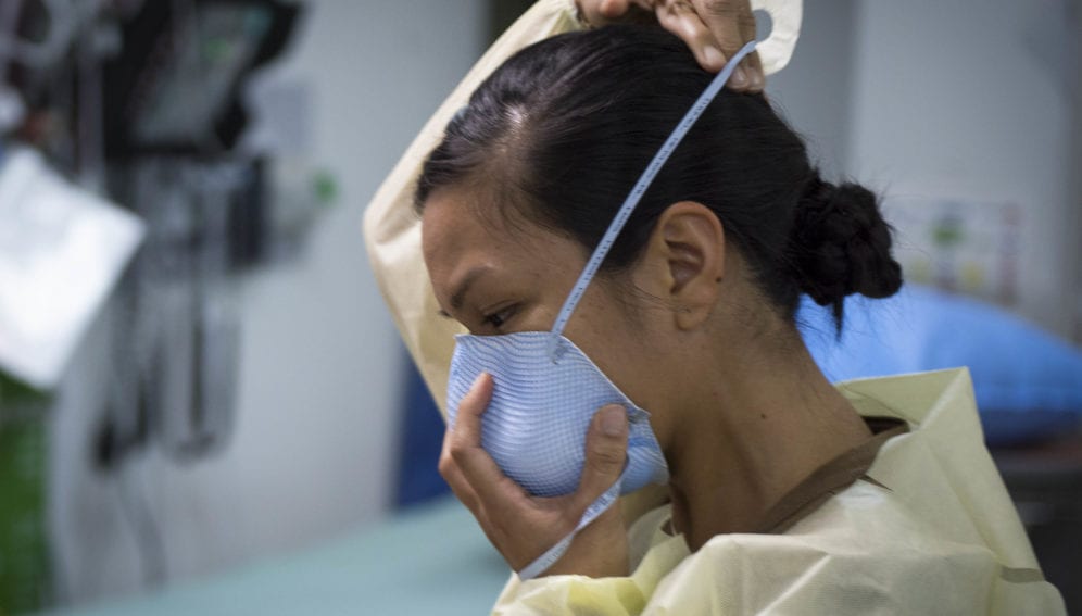 U.S. Navy Lt. Gail Evangelista, nurse, assigned to Naval Hospital Rota, Spain, dons a facemask prior to interacting with a patient at the Michaud Expeditionary Medical Facility (EMF) at Camp Lemonnier, Djibouti, April 16, 2020. Evangelista is part of a four-member team sent by Naval Forces Africa to augment critical positions within the EMF during the COVID-19 pandemic, enabling existing EMF staff to execute their primary mission of treating trauma patients. (U.S. Air Force photo by Senior Airman Dylan Murakami)