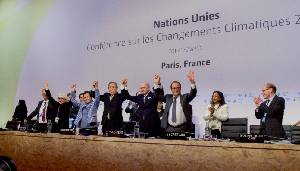 French_Foreign_Minister,_UN_Secretary-General_Ban,_and_French_President_Hollande_Raise_Their_Hands_After_Representatives_of_196_Countries_Approved_a_Sweeping_Environmental_Agreement_at_COP21_in_Paris_(2.jpg