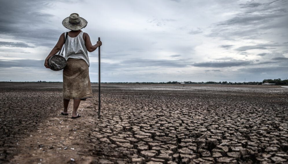 Women standing on dry soil and fishing gear, global warming and water crisis