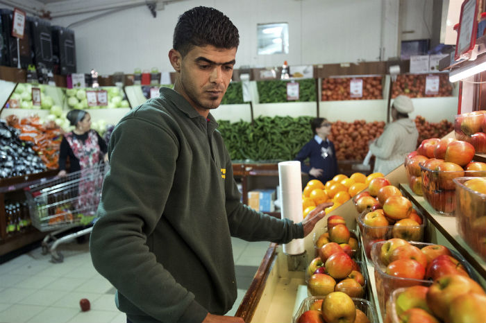 Rafat arranges a display of fruit at a branch