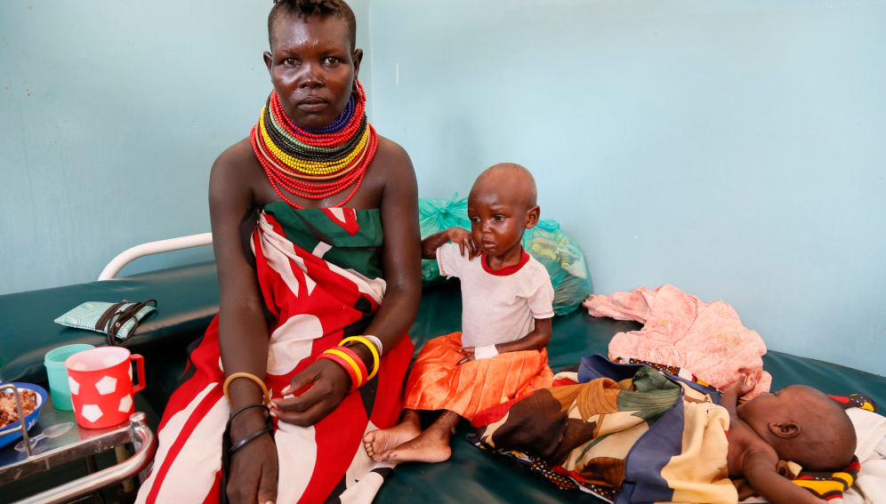 Two-year-old girl Erukudi, her mum Helen and baby sister, pictured in Lodwar Hospital, Turkana County, Northern Kenya. Erukudi is suffering from severe acute malnutrition, and is being treated with a high-energy milk formula to help her regain weight. Photo by UK Aid