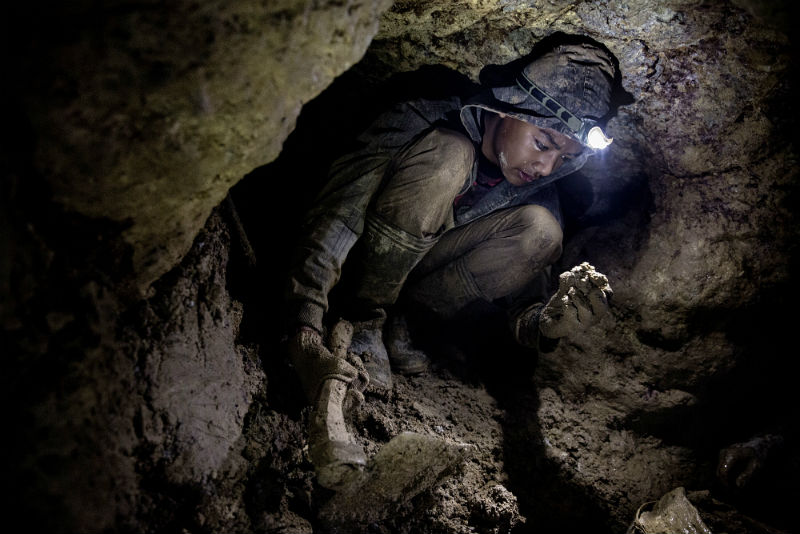 A young miner working in a narrow shaft