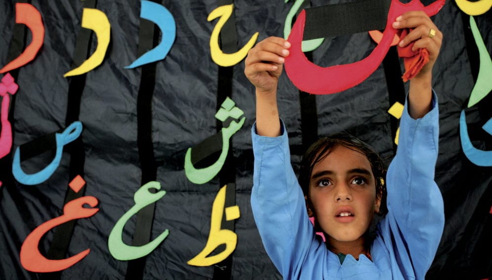Girl in school holding arabic letter.jpg