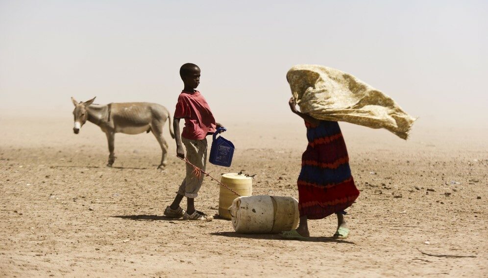 A boy and a woman struggle with the dusty wind looking for water in Wajir, Kenya