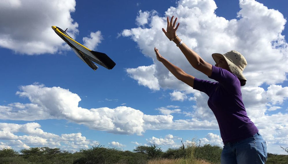 A female researcher flying a drone in the field in Namibia