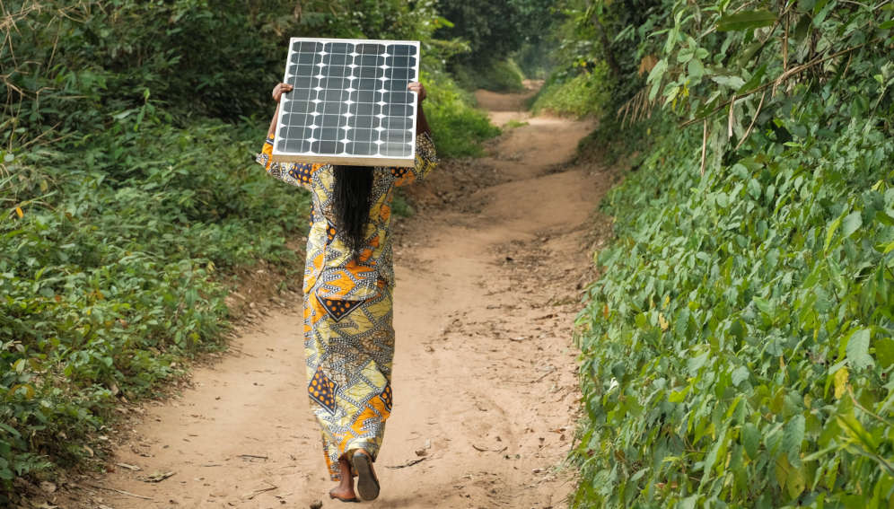 Woman carrying a solar pannel near Yangambi, DRC. Photo by Axel Fassio/CIFOR