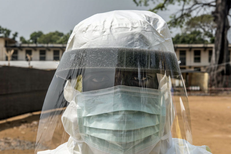 A burial team worker looks through the visor of his PPE