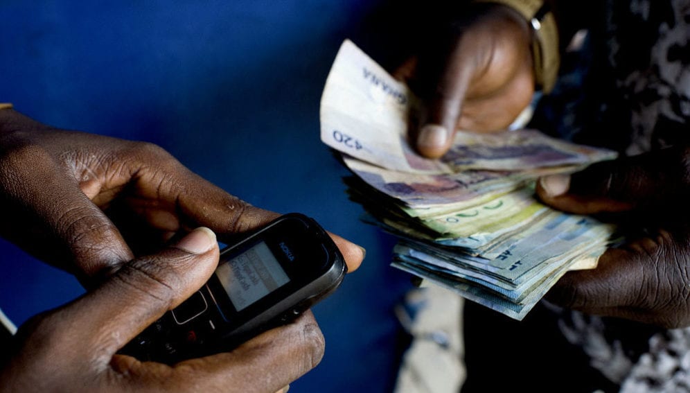 A customer uses his mobile phone to get cash from a Tigo Cash outlet