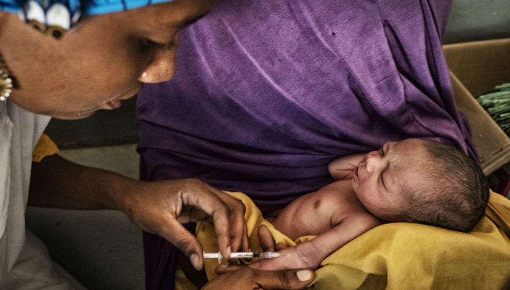 A health worker injects a baby with a vaccination