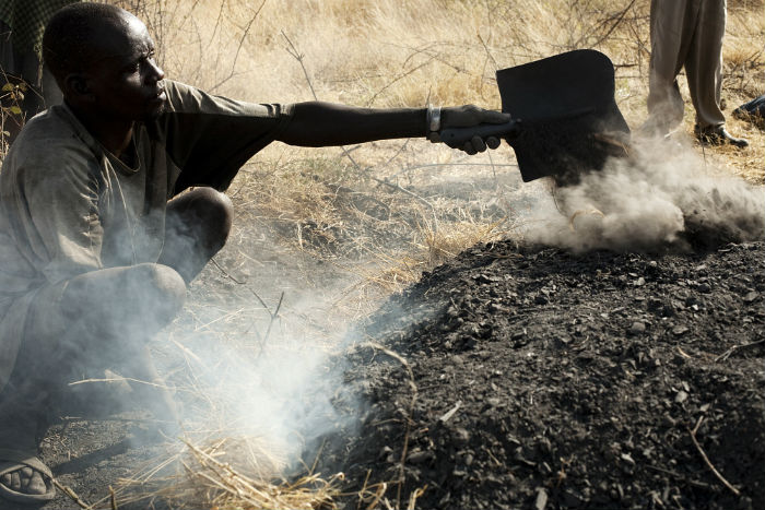 A man burns wood to make charcoal