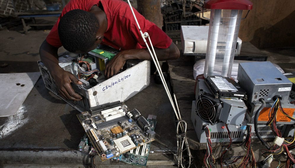 A man examines a hard drive at Agbogbloshie dump