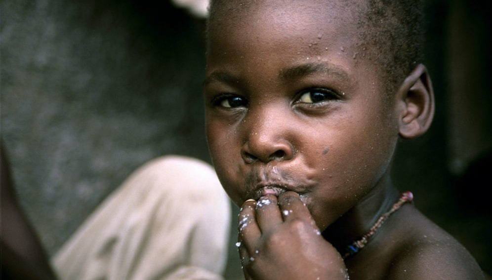A small boy eating maize porridge