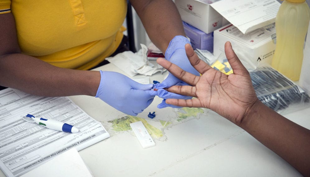 A woman has a blood prick sample taken for an HIV Test