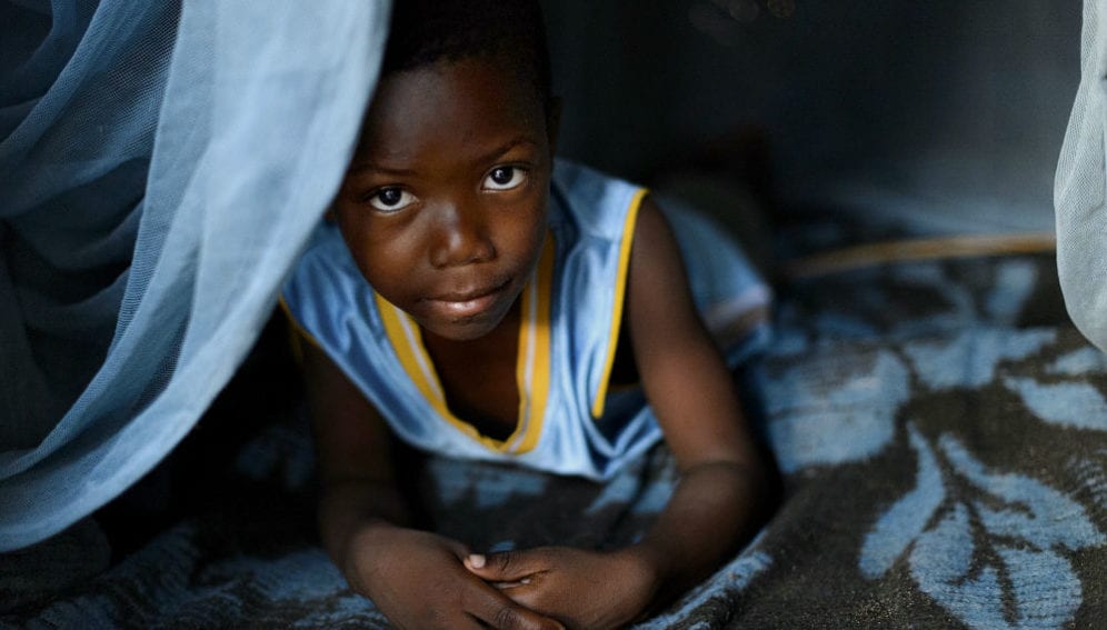 Boy peeks out from under his long-lasting insecticide-treated net