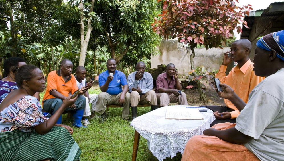 Farmers look at their mobile phones during farmer gatherin in Bwera, Uganda
