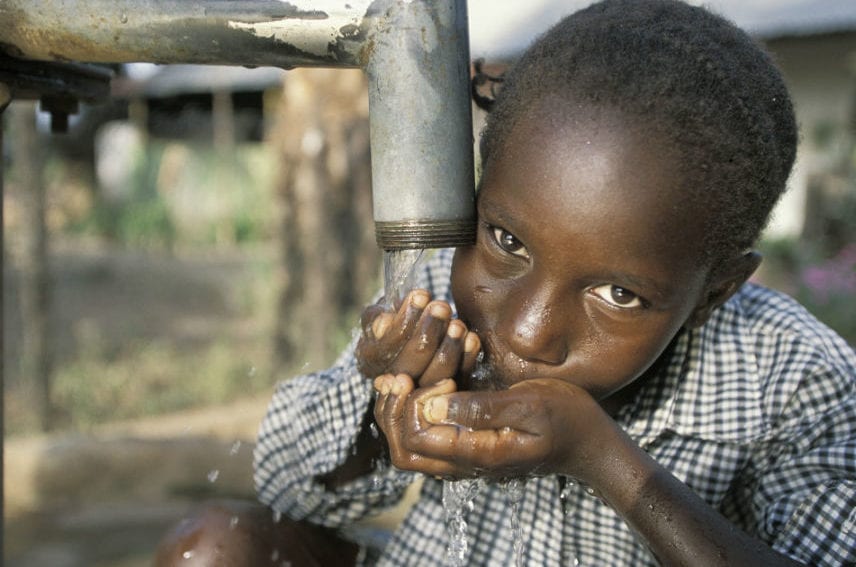 Little girl drinking clean water from a communal pump