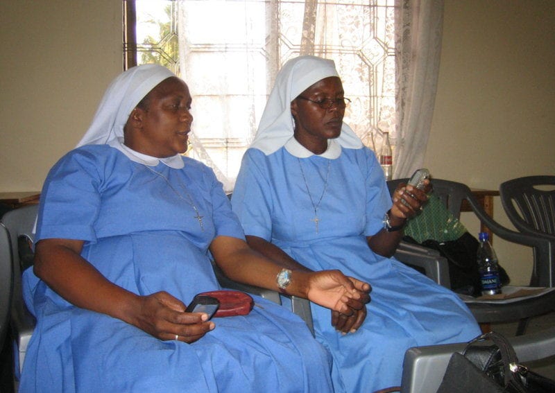 Medical sisters in Tanzania use a mobile phone while on a break of a Health Network meeting
