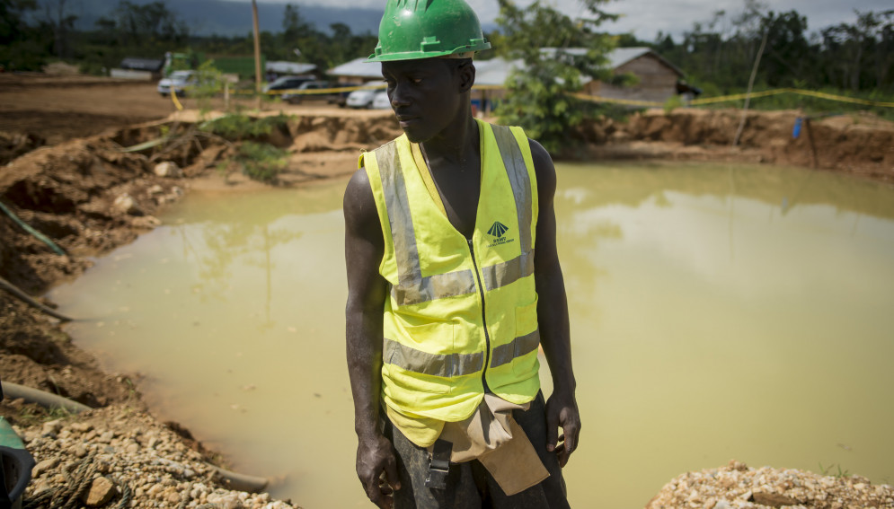 A miner overseeing the gold washing process at Babasala mining site in Kyebi stands next to a pond of water formed after gold prospecting.
