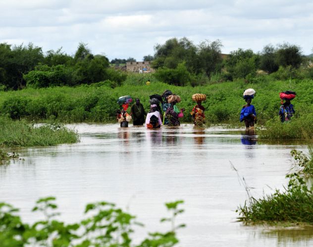 Women walk through floodwaters in Selibaby
