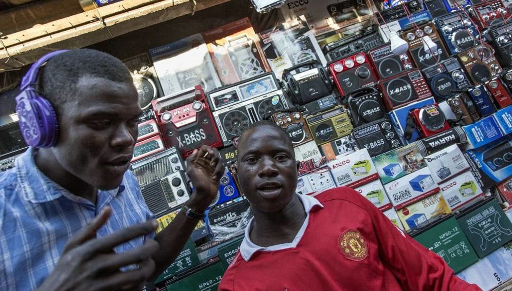 Young men listen to music in a market stall