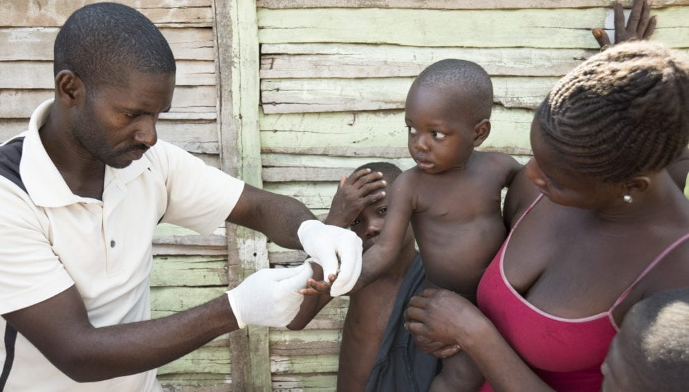 A Malaria Field Agent conducts a malaria rapid test on a small boy