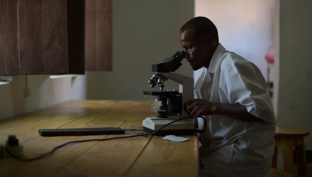 A lab technician checks a blood sample for malaria in Barawe, Somalia