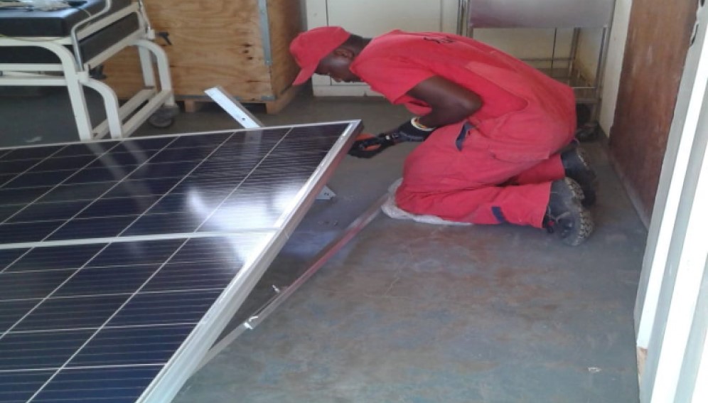 A technician fixing solar panels for a dispensary in Kenya
