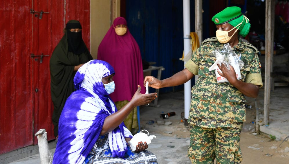 An AMISOM officer distributes face masks to businesswomen