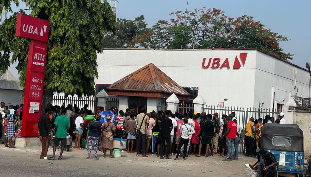 Nigerians queue at a bank to get cash after scarcity of the currency