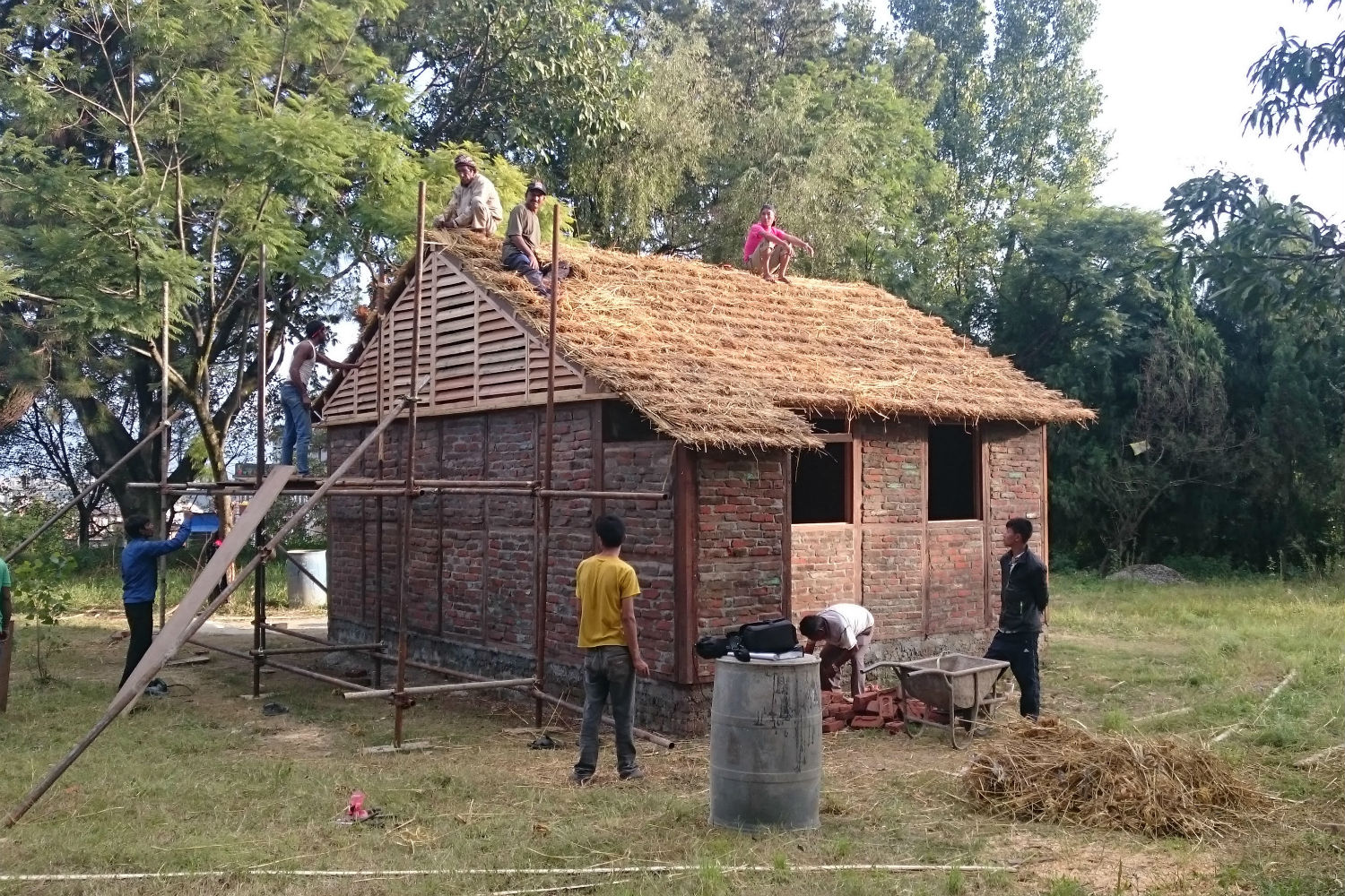 A disaster-resilient structure being built in Nepal. The wood-lattice frames are infilled with rubble left by the earthquake. The roof uses a robust truss system of cardboard tubes, and is thatched 
