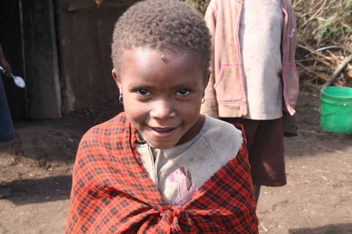 A young Maasai girl smiles cheekily at the camera. With the help of projects such as Maasai Stoves and Solar she can look forward to a brighter future.
