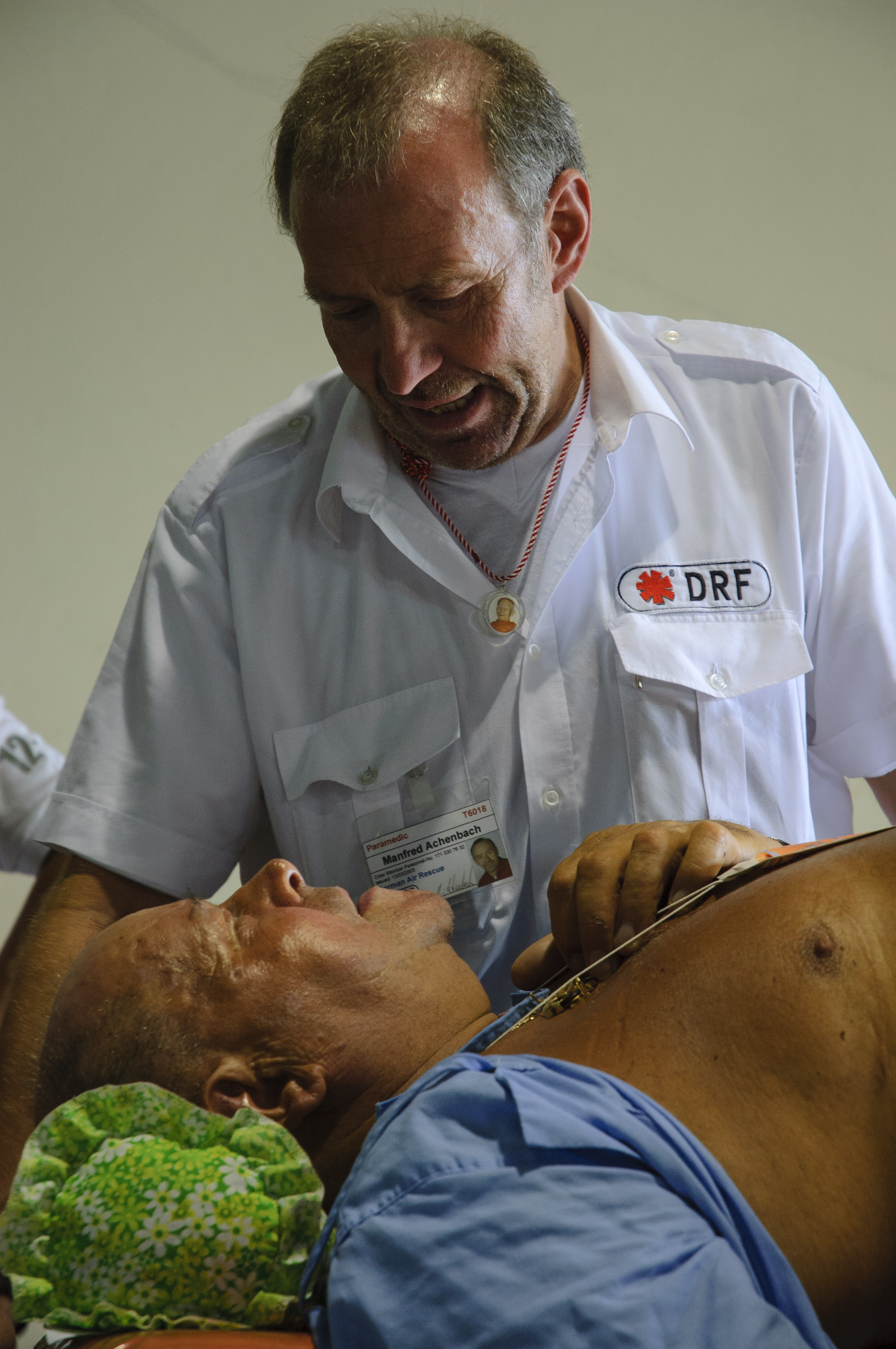 Manfred Achenbach, a Paramedic with German Air Rescue, talks with an injured man who was to be evacuated to Germany after the tsunami that hit Thailand