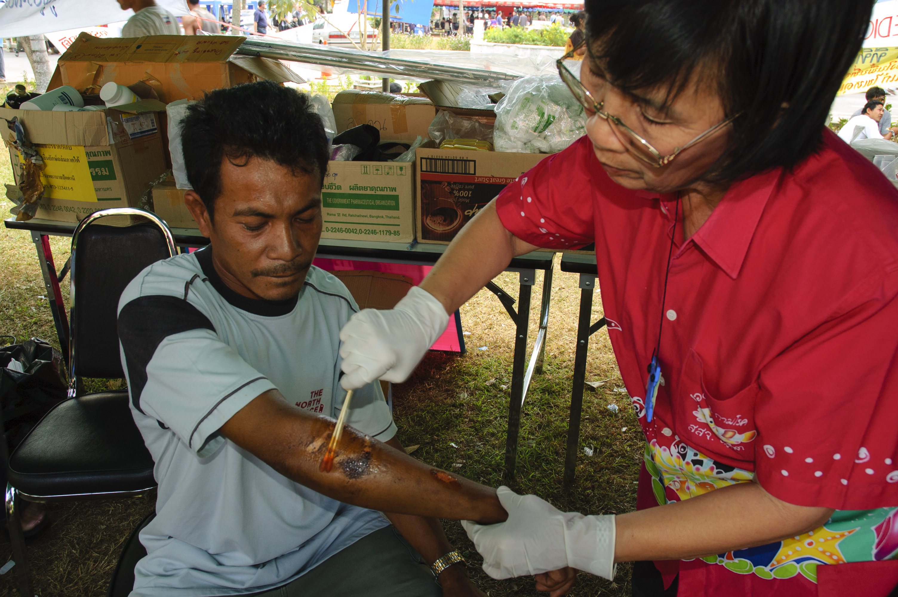 Thai nurse cleans the wounds of a Thai man who was injured while working in the debris