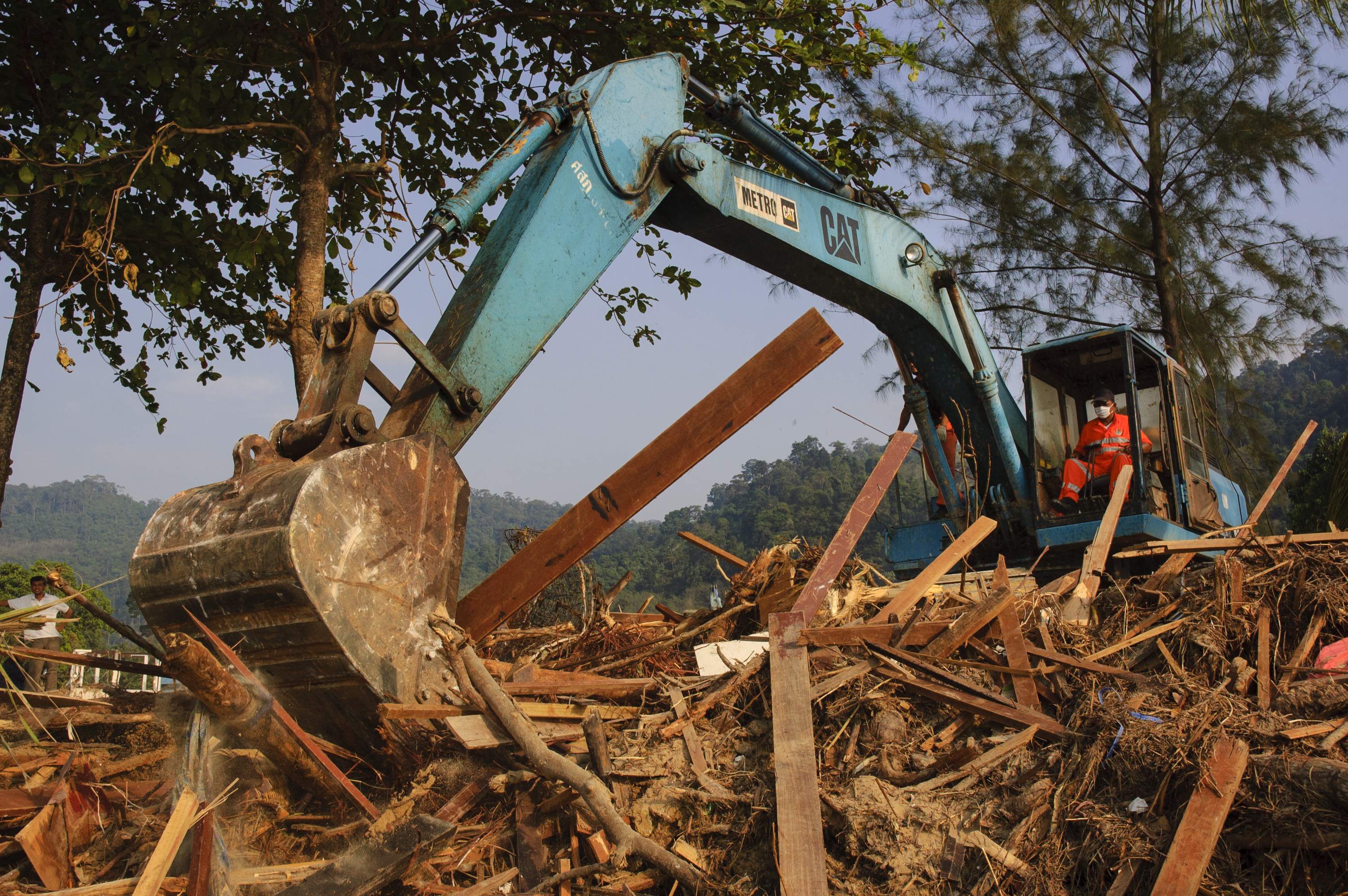 Rescue volunteer operates a power shovel while looking for corpses following the tsunami