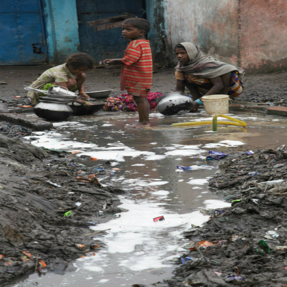 Children and women wash pots by a water pipe in Digha Maharajganj slum, India. The rubbish and waste water mix with the water from the pipe. These people belong to the Dalit ‘rag picking caste’. In Bihar, the caste system is still in evidence today. 
