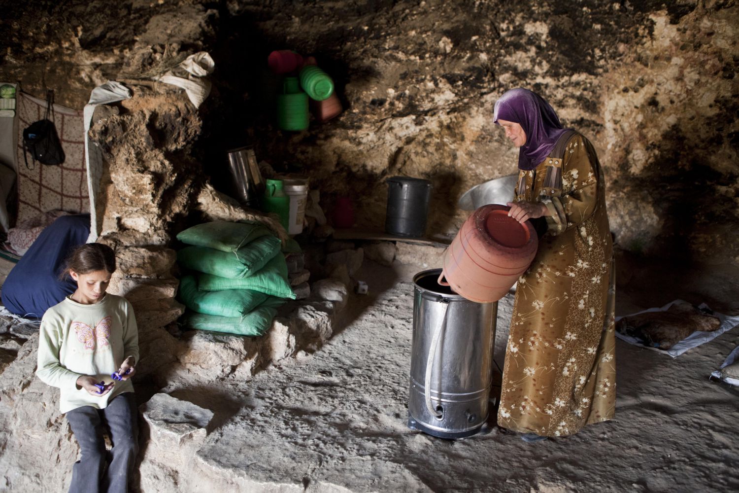 A woman pours milk into a new butter churner, powered by renewable energy. Electric churners slash the time it takes women to make butter and cheese — one of the staple livelihoods here. Many of the villagers in the Mount Hebron hills live in caves such as this one in Tuba 
