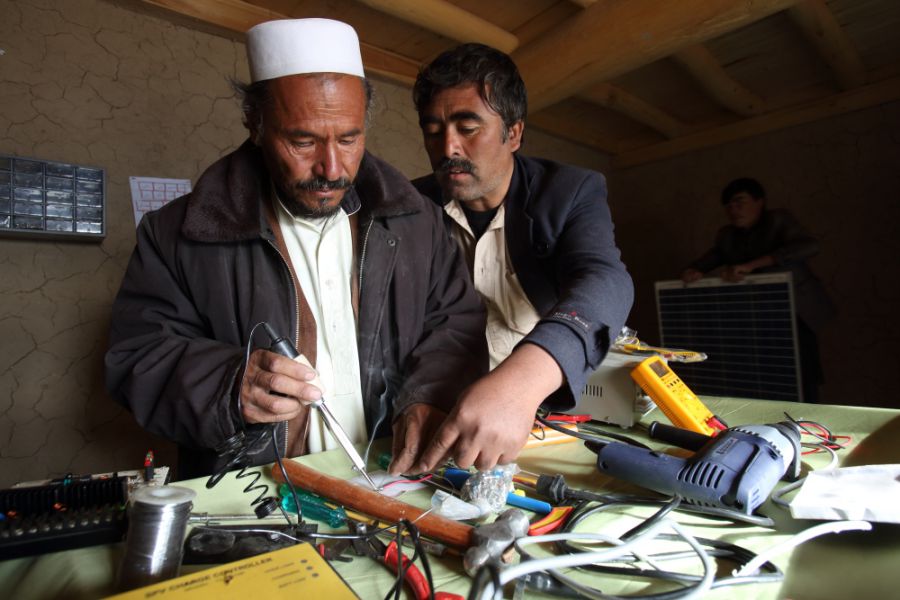 Mohammad Jan, a master ‘barefoot solar engineer’, instructing Alijan on preparing solar panels at a workshop in his home in the village. The project has funded ten local people, including Jan, to be trained in India. These, in turn, have trained a further 84 local engineers
