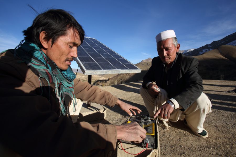 Huda Bakh, a 28-year-old barefoot solar engineer, assists Bostan with his recently installed solar system in Faizabad village, Daykundi province
