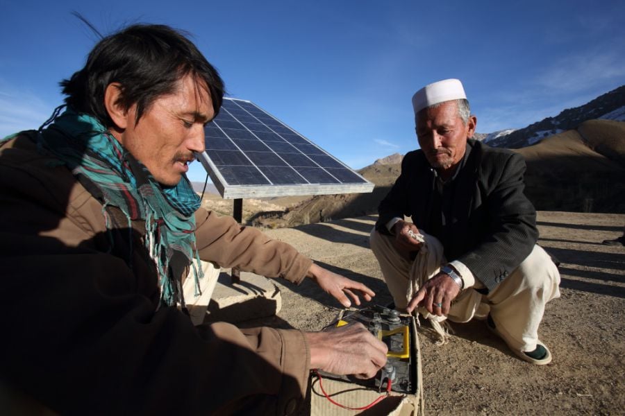 Huda Bakh, a 28-year-old barefoot solar engineer, assists Bostan with his recently installed solar system in Faizabad village, Daykundi province