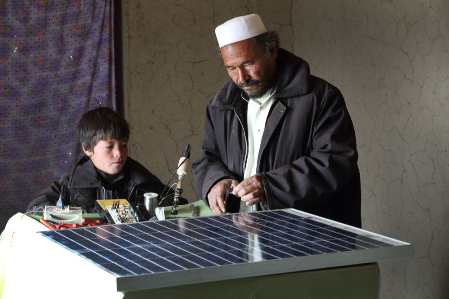 Alijan, a local barefoot solar engineer, is watched by his 12-year-old son in Palaj village, Daykundi province
