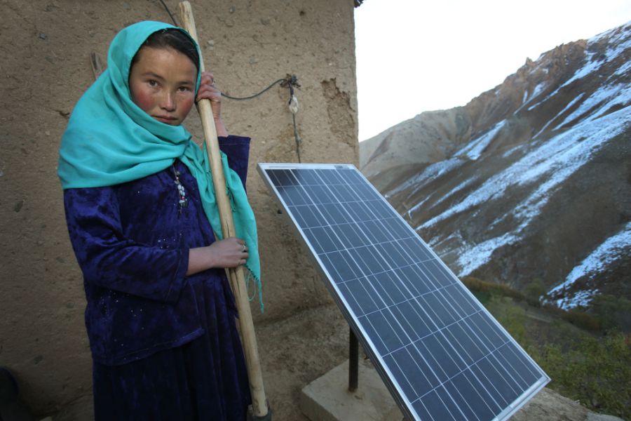 Fifteen-year-old Najiba stands in front of a solar panel installed by the project beside her house in Faizabad village, Daykundi province

